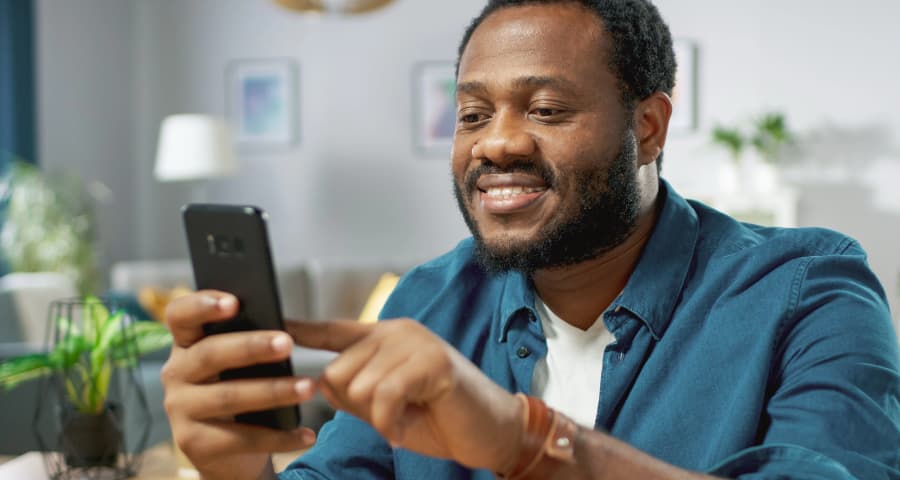 Man at home interacting with an app on his cell phone